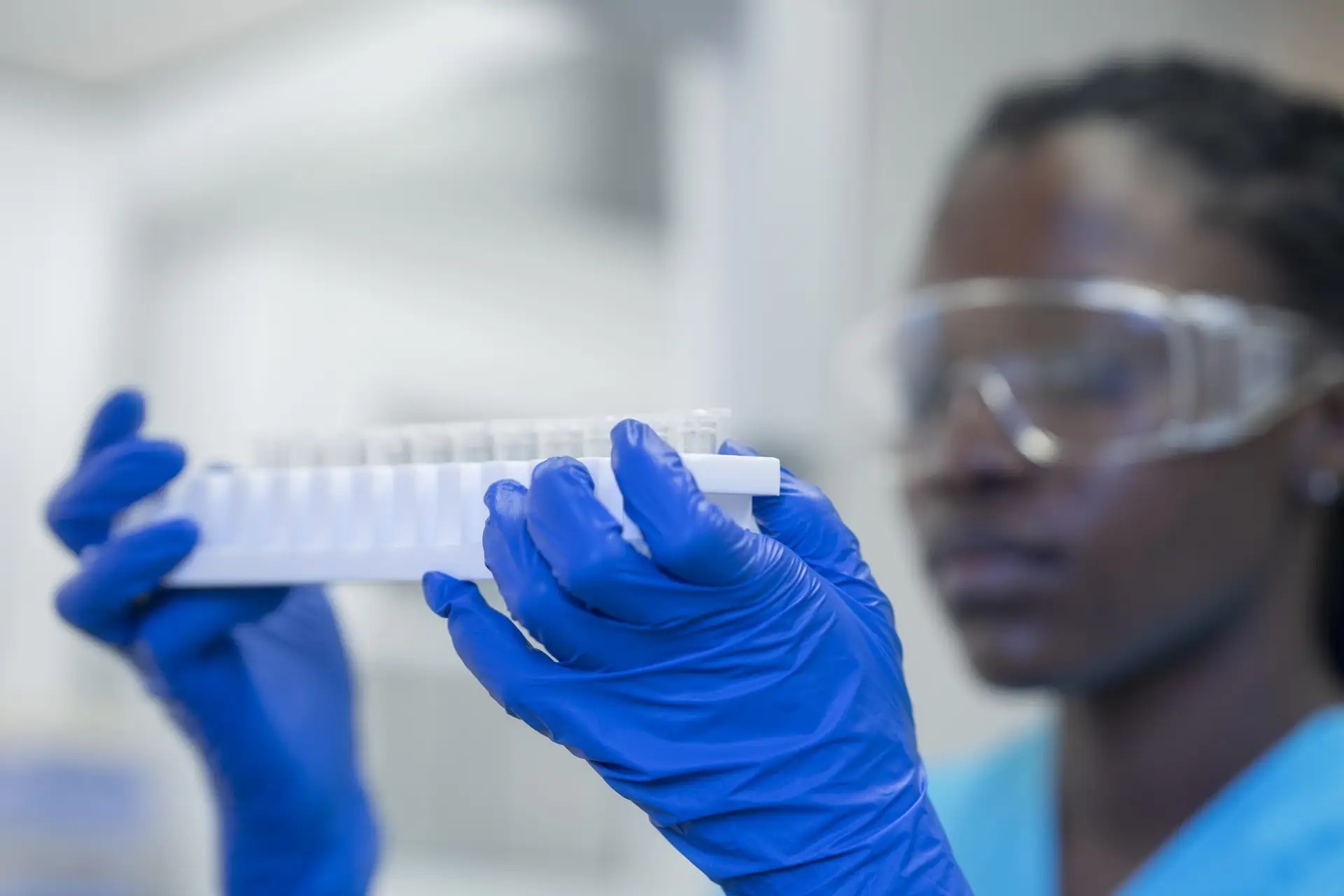 Accueil 1 Chercheuse effectuant une analyse en laboratoire QHSE, avec des éprouvettes et des gants de sécurité.